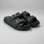 Black sandals with gold buckles on a gray background