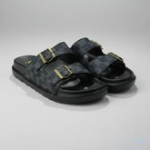 Black sandals with gold buckles on a gray background