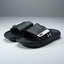 Black slide sandals with a brand logo on a gray background