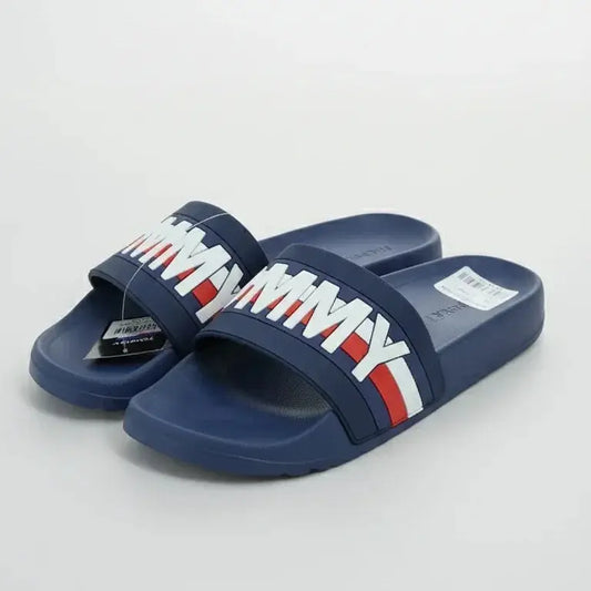 Pair of navy slides with a colorful strap on a light gray background
