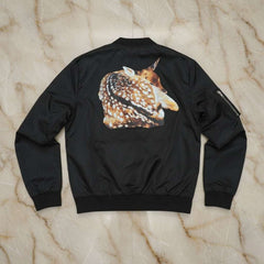 Black bomber jacket with a deer graphic on the back, laid flat on a marble surface.