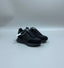 An all-black Alexander McQueen Sprint Runner sneaker being held to show its suede and leather details, embossed side logo, and thick chunky sole.