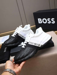 Black and white sneakers with 'BOSS' branding held by a hand, with a black 'BOSS' box in the background.