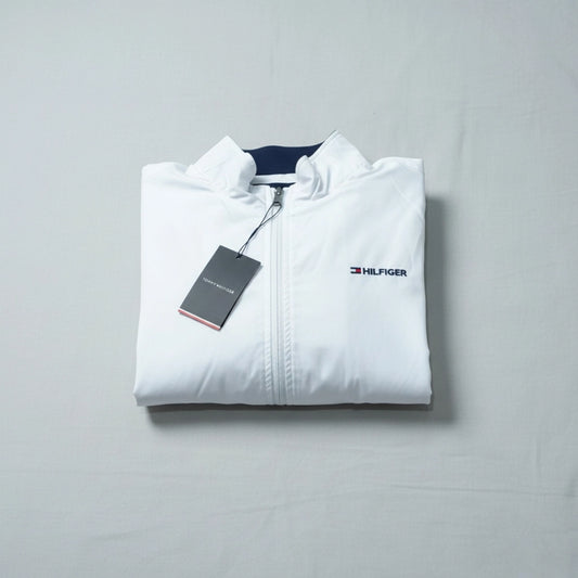 Folded white jacket with Tommy Hilfiger logo on a gray background