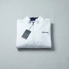 Folded white jacket with Tommy Hilfiger logo on a gray background