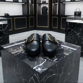 Black shoes on a marble platform with a high-end store interior in the background.
