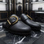 Black shoes with gold buckles on a marble surface, with 'UNIVERSES' branding above.