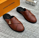 Brown Louis Vuitton shoes with a gold logo on a gray surface, next to an orange box.