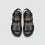 Black sandals with patterned straps on a wooden surface