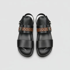 Black sandals with patterned straps on a wooden surface