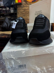 Front profile of the black Alexander McQueen Sprint Runner sneakers, highlighting the lacing system and logo on the tongue