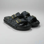 Black sandals with gold buckles on a gray background