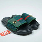 Green and black slide sandals with a red stripe on a white background
