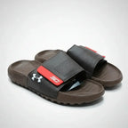 Brown slides with a red and black strap on a light gray background