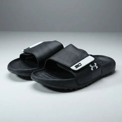 Black slide sandals with a brand logo on a gray background