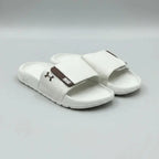 White sandals with a brown logo on a gray background