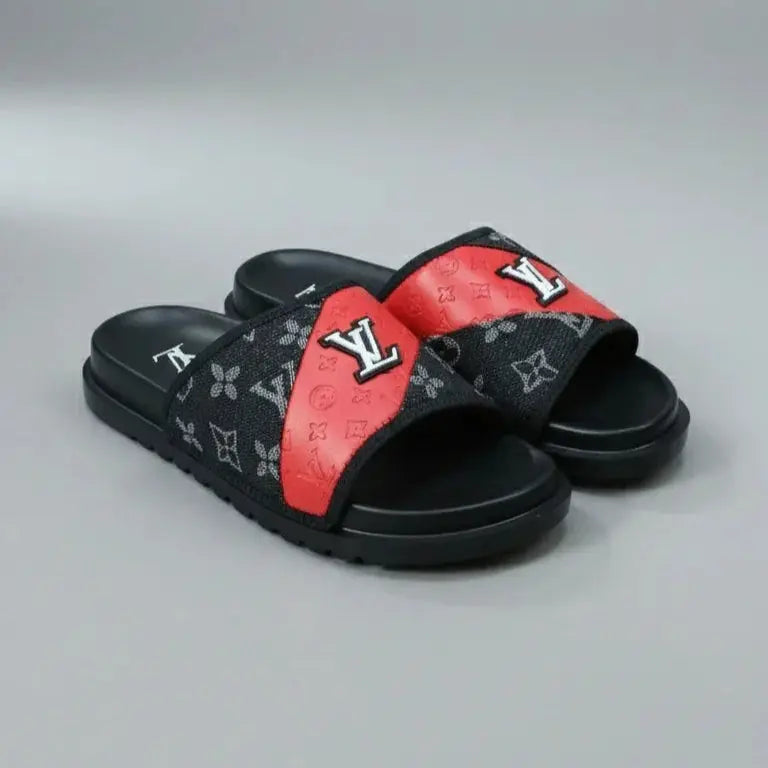 Black and red slide sandals with a brand logo on a gray background