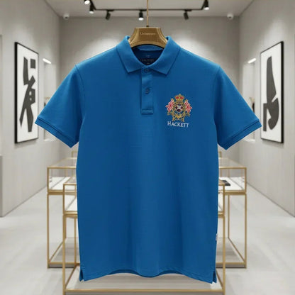 Blue polo shirt with a logo on a hanger in a modern interior setting