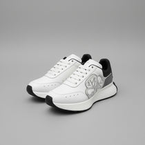 White sneakers with black accents on a box, with Alexander McQueen branding visible.