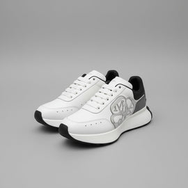 White sneakers with black accents on a box, with Alexander McQueen branding visible.