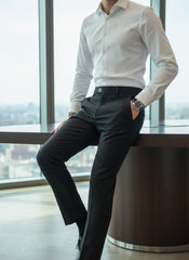 Person wearing a white dress shirt and black pants in an office setting with large windows.