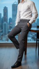 Man in formal attire standing in a room with a cityscape view