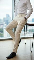 Person wearing a white shirt and beige pants in an office setting with a cityscape view.