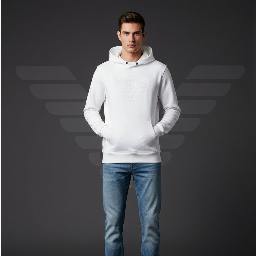 Man wearing a white hoodie and blue jeans against a dark background