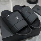 Black slides with Prada logo on a gray surface