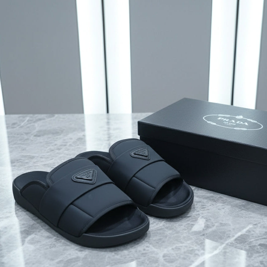 Black slides with a triangular logo on a marble surface next to their packaging box.