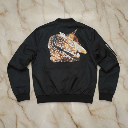 Black bomber jacket with a deer graphic on the back, laid flat on a marble surface.