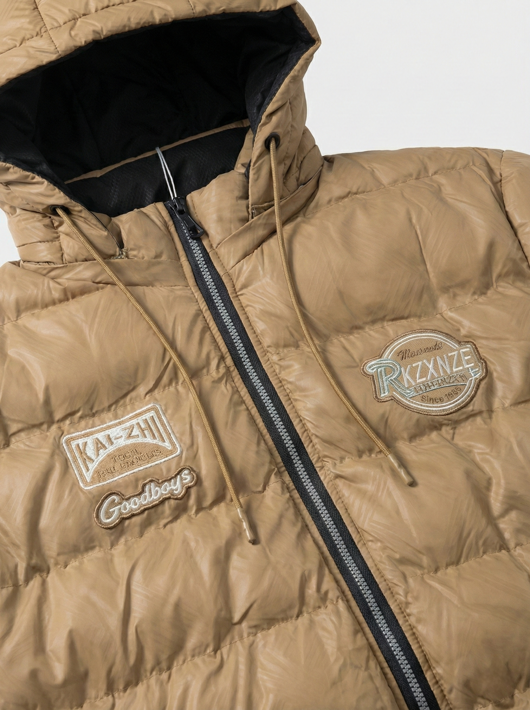 Close-up of a brown puffer jacket with visible branding on a light gray background