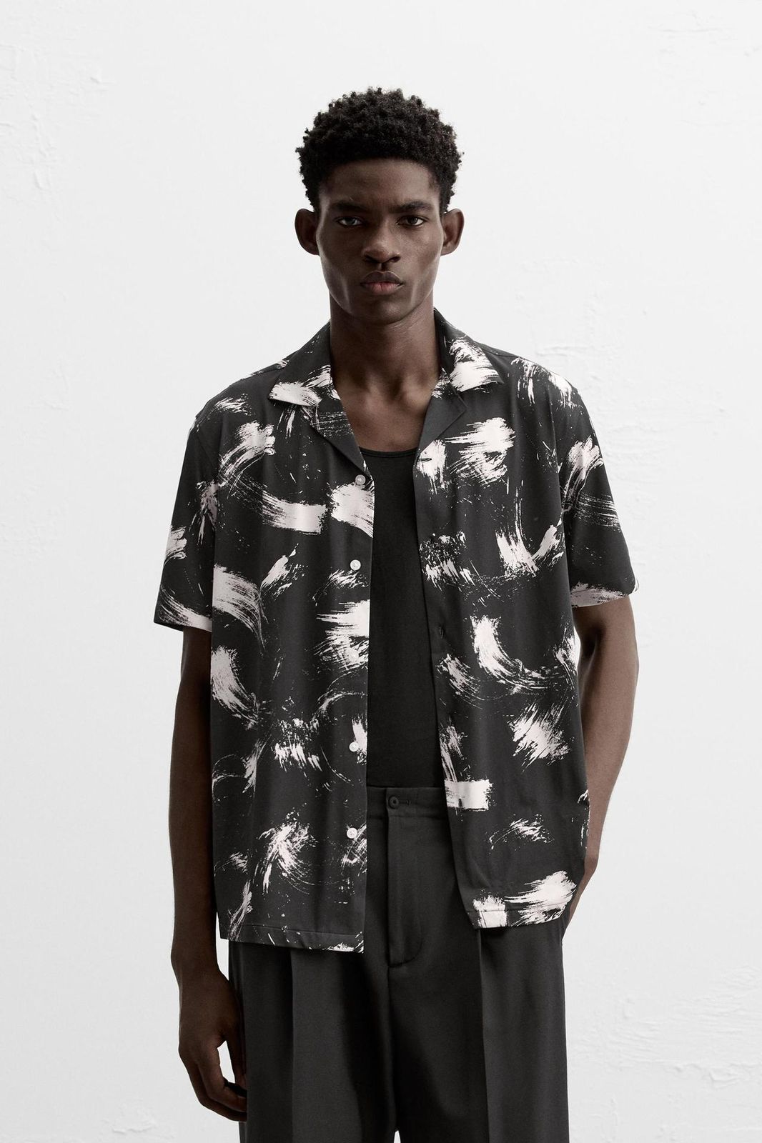 Man wearing a black and white patterned shirt on a white background