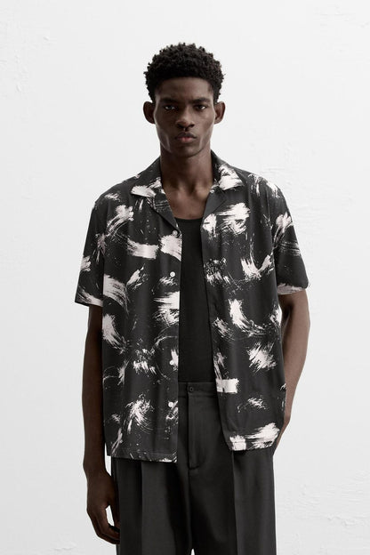 Man wearing a black and white patterned shirt on a white background