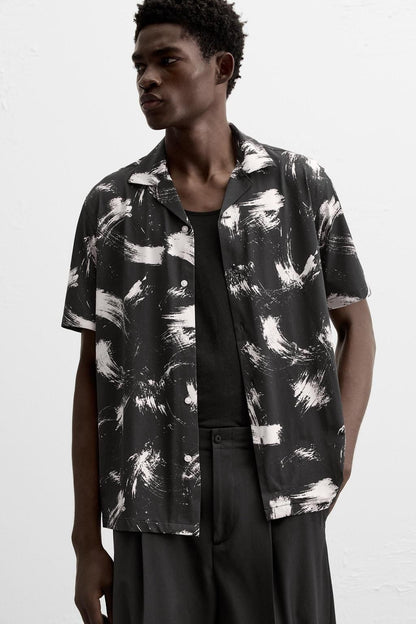 Man wearing a black and white abstract patterned shirt on a white background