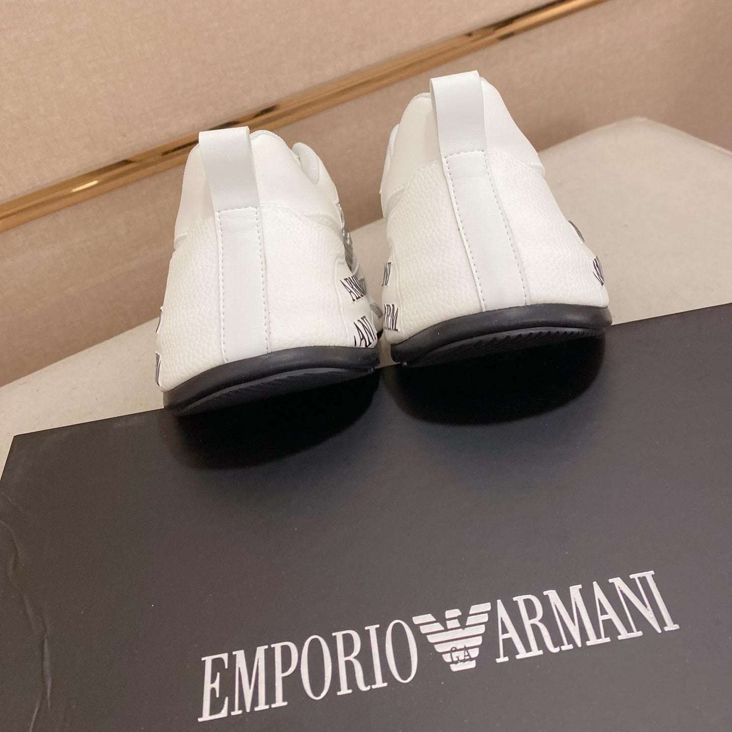 White high-top sneakers on a black Emporio Armani box with a beige background