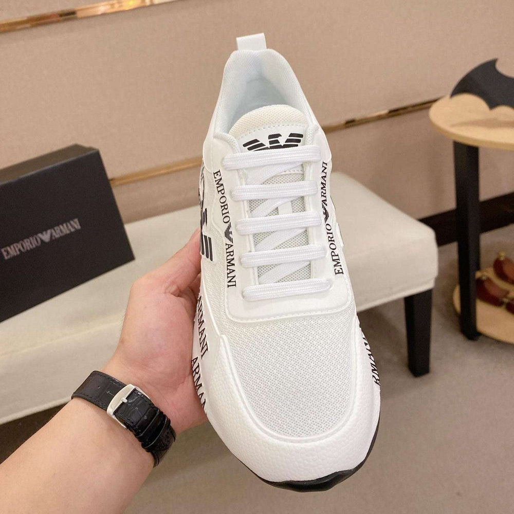 White sneaker with brand logo held by a hand, with a blurred indoor background