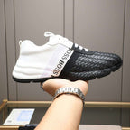 Black and white sneaker with 'BOSS' branding held by a person wearing a watch.