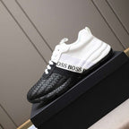 Black and white sneakers with 'BOSS' branding on a black platform against a neutral background.