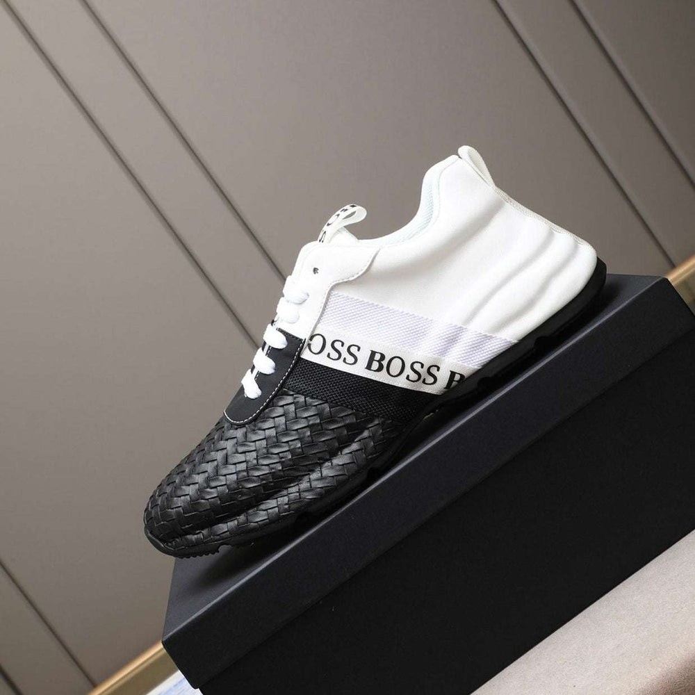 Black and white sneakers with 'BOSS' branding on a black platform against a neutral background.