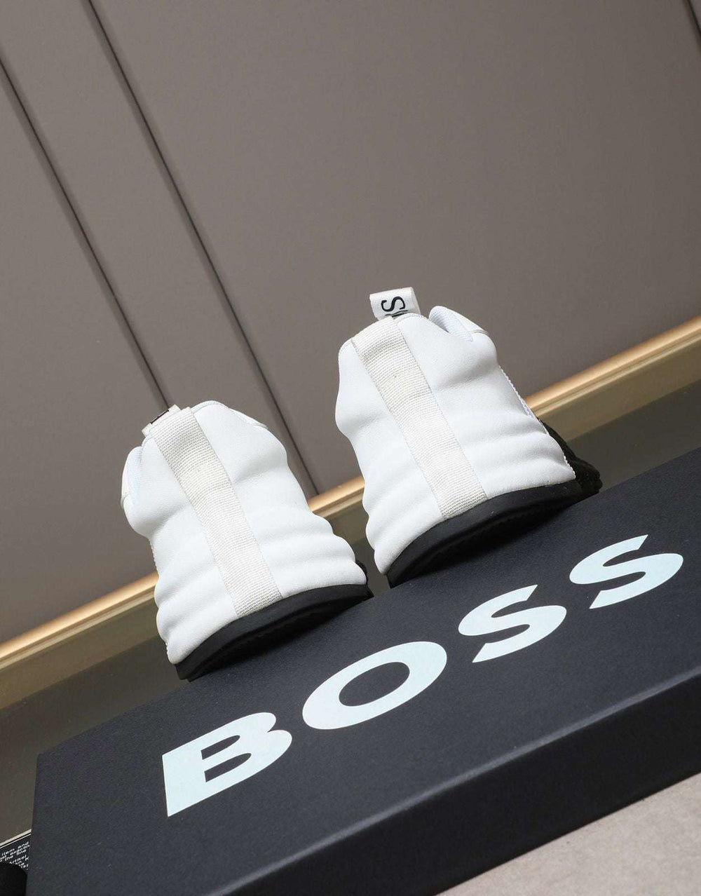 White gloves on a black 'BOSS' branded box against a gray background
