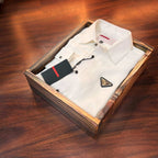 White dress shirt with a triangle logo in a wooden box on a wooden surface
