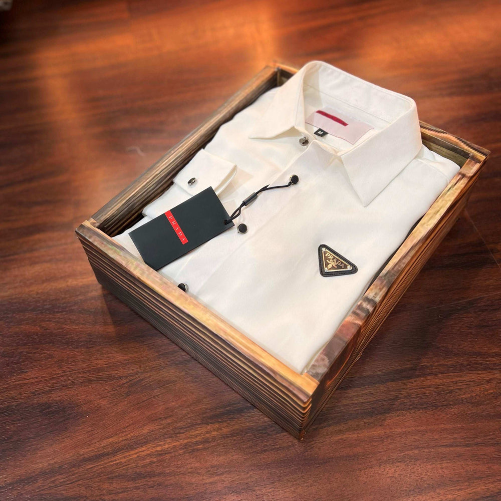 White dress shirt with a triangle logo in a wooden box on a wooden surface