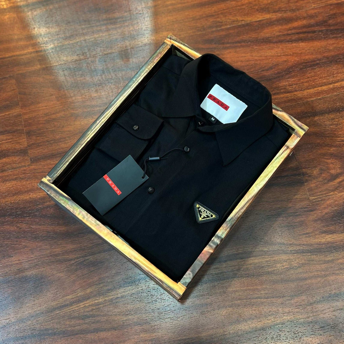 Black shirt with a tag in an open box on a wooden surface