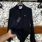Black shirt on a hanger with a Prada tag against a background of dollar bills and 'UNIVERSES' text.