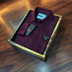 Maroon shirt with a brand logo in a wooden box on a wooden surface