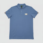 Blue polo shirt with a brand logo on a brown leather couch.