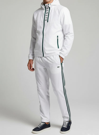 Person wearing a white tracksuit with brand logo on a plain background