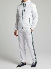Person wearing a white tracksuit with brand logo on a plain background