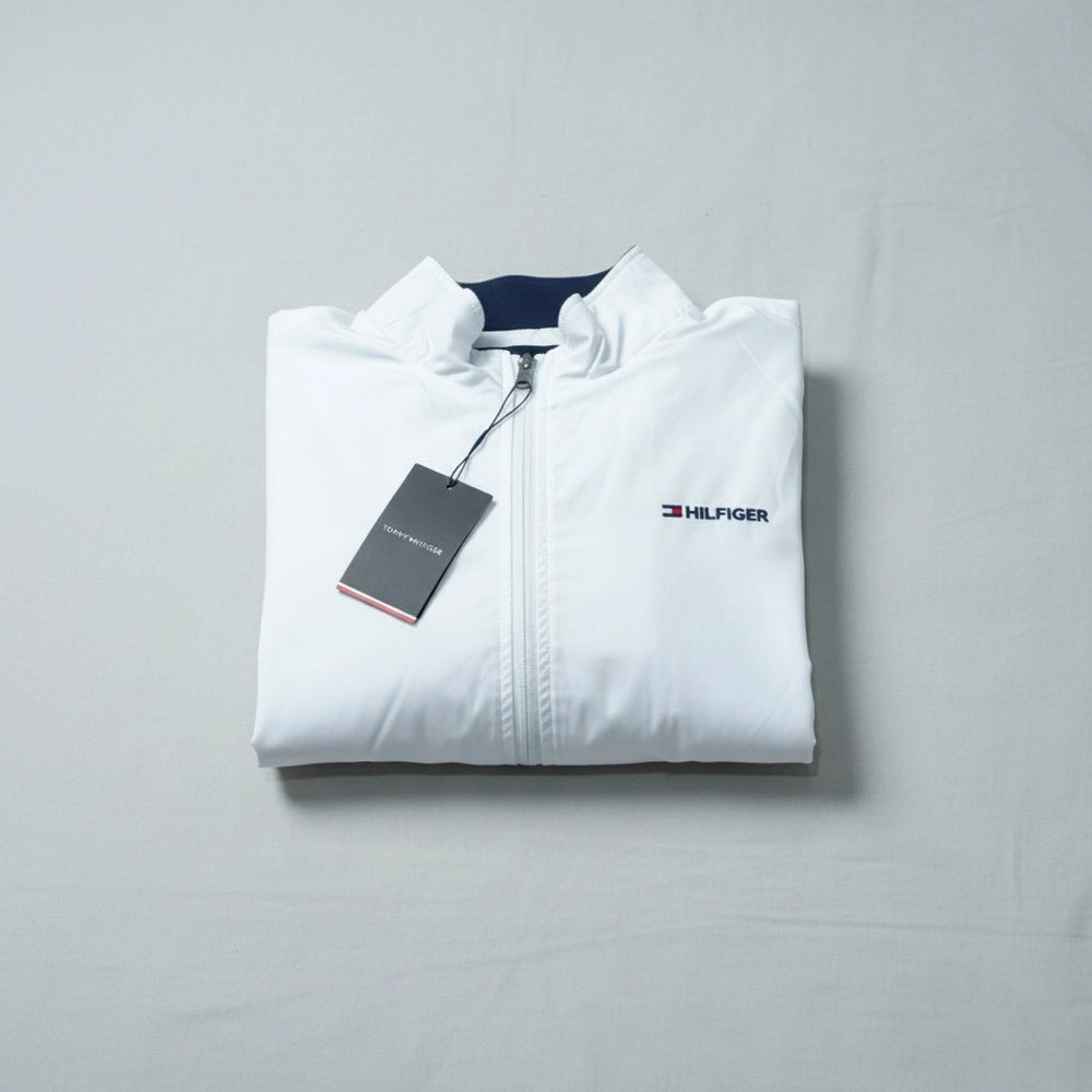 Folded white jacket with Tommy Hilfiger logo on a gray background